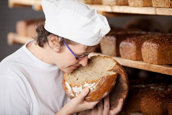 Female bakery worker smelling bread — Stock Photo, Image