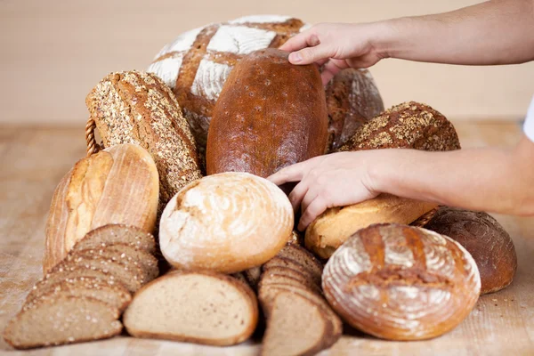 De verkoopster handen inrichtend brood — Stockfoto