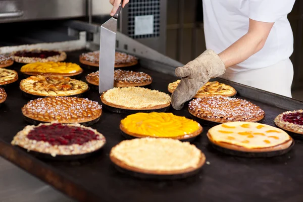 Lavoratore cottura varie torte — Foto Stock