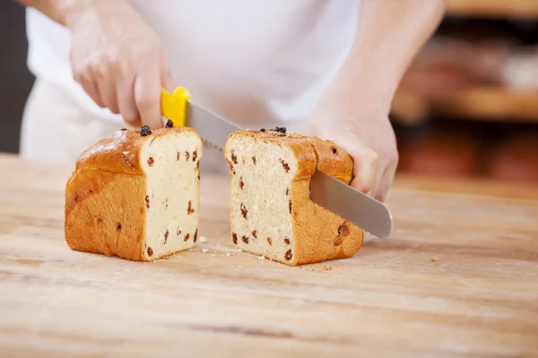Man cutting raisin bread loaf — Stock Photo, Image
