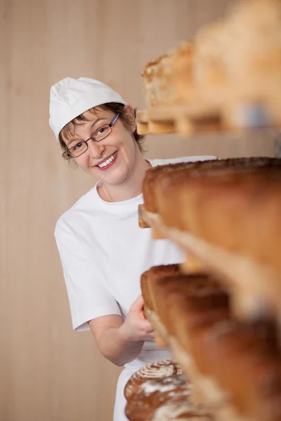 Chef de pie junto al armario lleno de panes — Foto de Stock