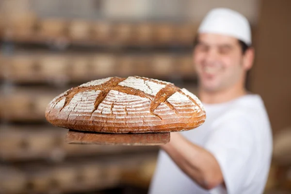 Worker at bakery showing bread — Stock Photo, Image
