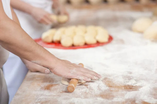 Chef rolling dough with coworker — Stock Photo, Image