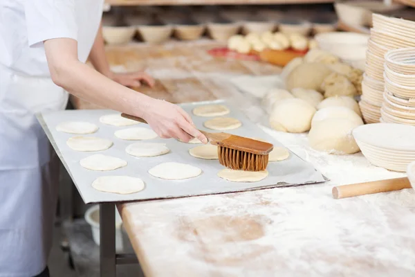 Chef aplica mantequilla sobre la masa en la panadería —  Fotos de Stock