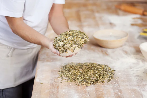 Chef holding dough covered with seeds — Stock Photo, Image