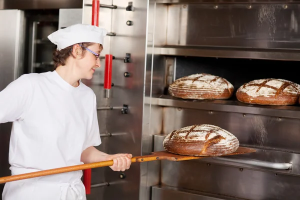 Kvinnlig arbetare baka bröd i köket — Stockfoto
