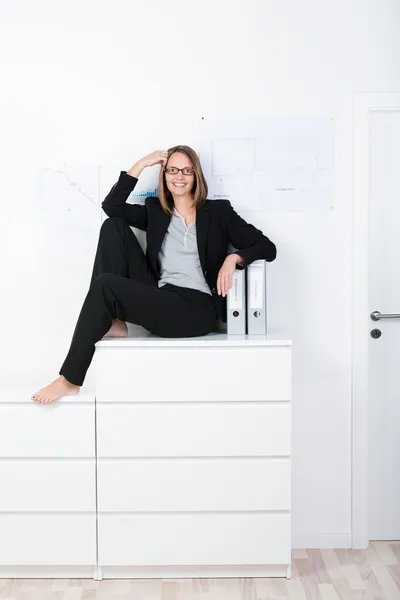 Affärskvinna sitter på arkivskåp — Stockfoto