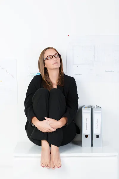 Barefoot businesswoman sitting thinking — Stock Photo, Image