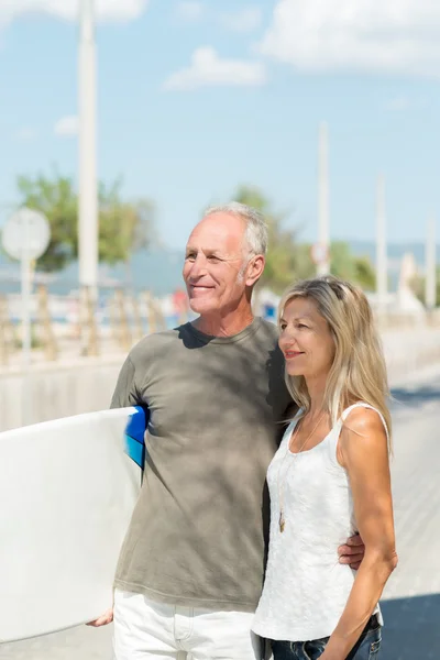 Middle-aged couple carrying surf board — Stock Photo, Image