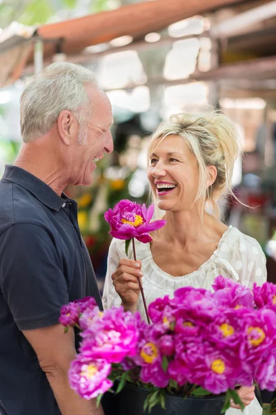 Vivacious couple celebrating with flowers — Stock Photo, Image