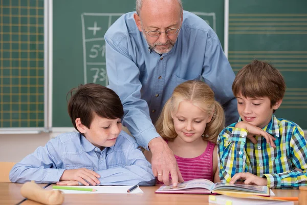 Profesor explicando libro de texto a sus estudiantes — Foto de Stock