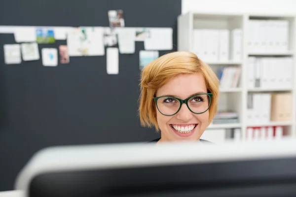 Geschäftsfrau hinter Monitor schaut auf — Stockfoto