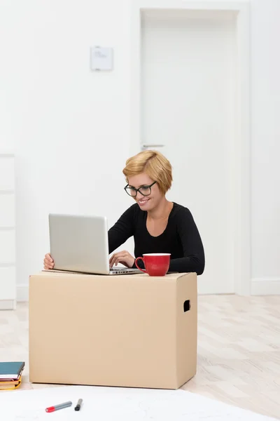 Piękna kobieta przy użyciu kartonie jako biurko — Zdjęcie stockowe