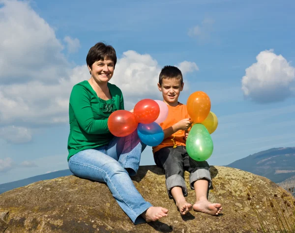 Zittend op de steen en gelukkige familie — Stockfoto