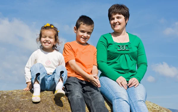 Familia feliz sentada en la piedra — Foto de Stock