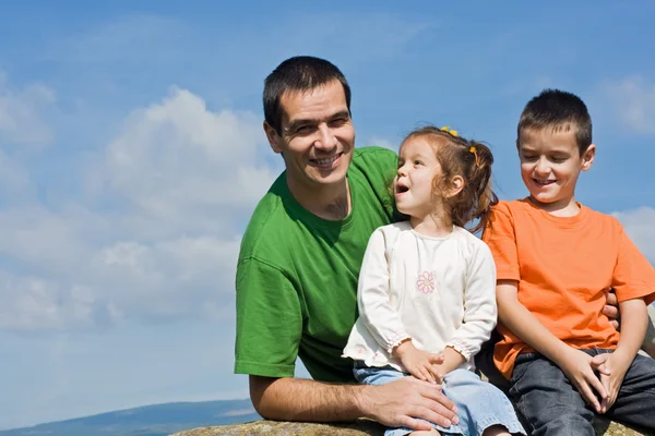 Happy family sitting on the stone — Stock Photo, Image