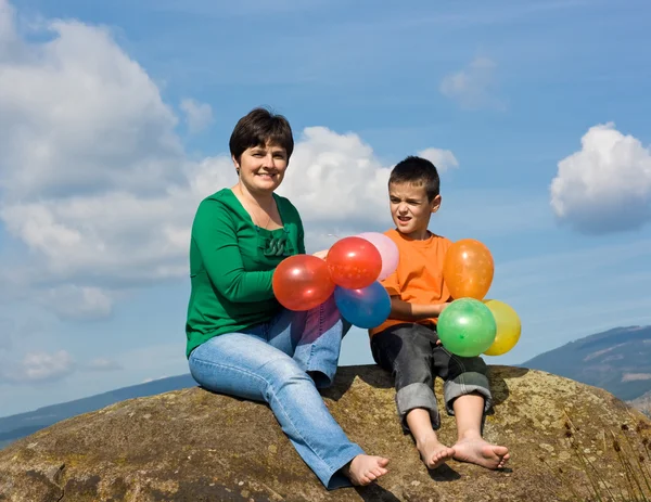 Familia feliz sentada en la piedra — Foto de Stock