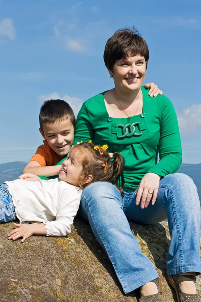 Familia feliz sentada en la piedra — Foto de Stock