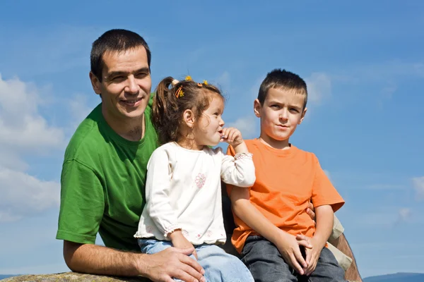 Familia feliz sentada en la piedra — Foto de Stock