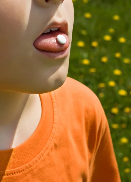 Niño usando la píldora anti-alergias Imágenes de stock libres de derechos