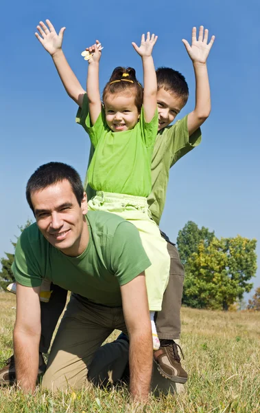 Familia feliz jugando en el prado — Foto de Stock