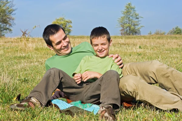 Boy y su padre tendidos fuera Imágenes de stock libres de derechos