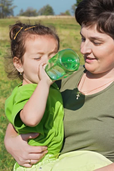 Niña bebiendo en la mano de su madre — Foto de Stock