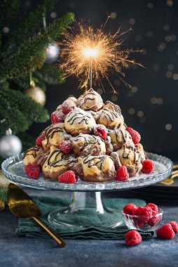 Çikolata kremalı ve ahududulu profiterol keki. Kek tabağında roquembouche. Noel tatlısı. Seçici odak