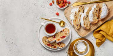 Noel Stollen. Geleneksel Alman Noel pastası. Bir fincan çay ve doğranmış çalgılarla dolu bir masanın en üst görüntüsü..