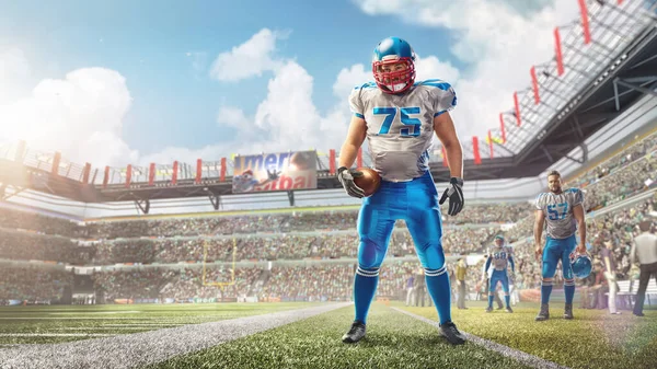Sport. Americký fotbalista stojí na stadionu a drží v ruce míč. Denní stadion plný fanoušků — Stock fotografie