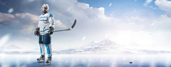 Professional ice hockey player in the mountains. Hockey player in a helmet and gloves and a stick in his hands on ice. Sports emotions. Winter background. Sport