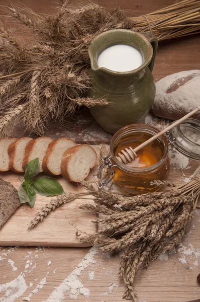 Rolos, pão e farinha em mesa de madeira — Fotografia de Stock