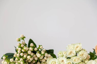 Bağ beyaz ahşap bir masanın kenarında çiçekler ve yeşiller