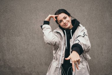 Sokakta dans eden mutlu bir kız. Güzel esmer neşe ve gülücükler. Gençler arasında popüler sokak dansları. Bej pelerinli mutlu kız