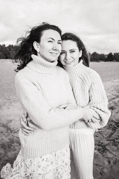 Czarno-białe zdjęcie z przytulającymi się dziewczynami. Dwie brunetki w ciepłych swetrach. Bliskie związki między siostrami. Silne więzi rodzinne u dzieci. — Zdjęcie stockowe