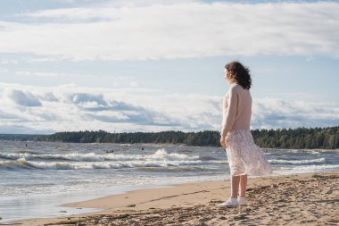 İnsanın doğayla bütünlüğü. Bir kız deniz kenarında kumlu bir sahil boyunca yürüyor. Yalnız bir kız okyanusun kenarında yürüyor. Modern insanlarda yalnızlık korkusu