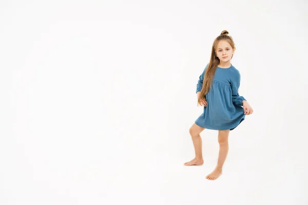 Милая маленькая девочка в синем платье. Место для текста и рекламы. Красивый ребенок с длинными светлыми волосами. Девушка в полном росте на монохромном фоне. — стоковое фото