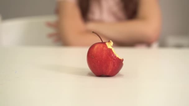 Dítě odmítá jíst zdravé jídlo. Malá holka odstrčí jablko. Detailní záběr pokousaného jablka. — Stock video