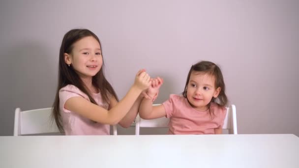 A kislányok kibékülnek. A nővérek jól érzik magukat. A gyerekek boldogan ölelkeznek. Öleld meg a húgodat! — Stock videók