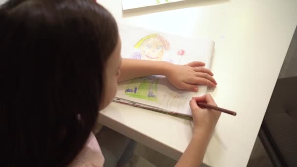 El niño dibuja con lápices de colores. Dibujos de cerca del niño. Una chica con una camiseta rosa dibuja un cuadro — Vídeos de Stock