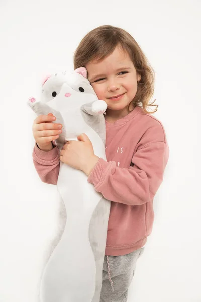 Маленькая девочка обнимает свою любимую игрушку. Девочка крепко держит кота. Комфортные подушки. — стоковое фото