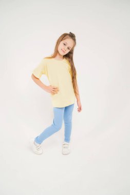Sarı tişörtlü ve mavi pantolonlu bir çocuk. Uzun sarı saçlı bebek. Hafif bir arka planda model görünümlü güzel bir kız
