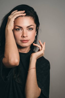 Güzel bir esmerin yaratıcı portresi. Monokromatik arka planda bir kızın dikey fotoğrafı. Güzel dans eden eller kızların yüzüne.