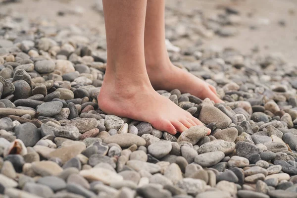 Lapos lábak megelőzése gyermekeknél. A gyermek mezítláb jár a köveken. A valgusz láb kezelése gyermekeknél és felnőtteknél. Közelkép a gyerekek lábáról a sziklákon. — Stock Fotó