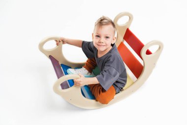 Küçük bir çocuk salıncakta sallanıyor. Sarı saçlı bebek. Monokromatik spor giyimli bir çocuk..