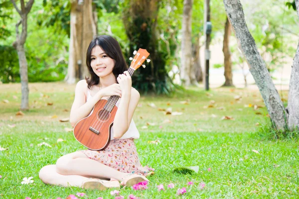 Asiatisk tjej med ukulele gitarr utomhus — Stockfoto