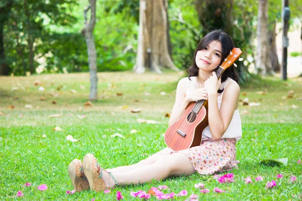 Asiatisk tjej med ykulele gitarr utomhus — Stockfoto