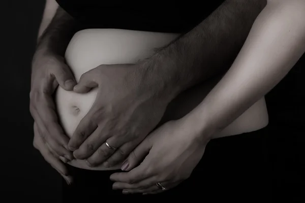 Mani dell'uomo sulla pancia di incinta Immagine Stock
