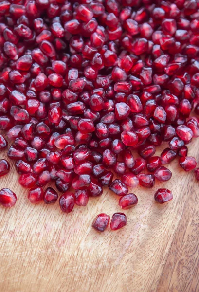 Pomegranate seeds on a wooden board — Stock Photo, Image