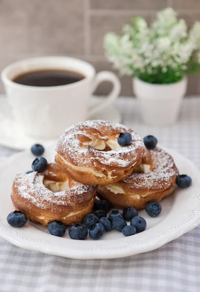 Cream puffs or choux pastry rings with blueberries on the plate — Stock Photo, Image